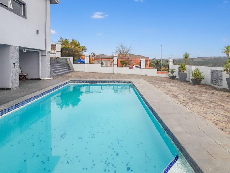 Outdoor pool area featuring a rectangular swimming pool, paved patio space, and perimeter boundary walls with stone accents.