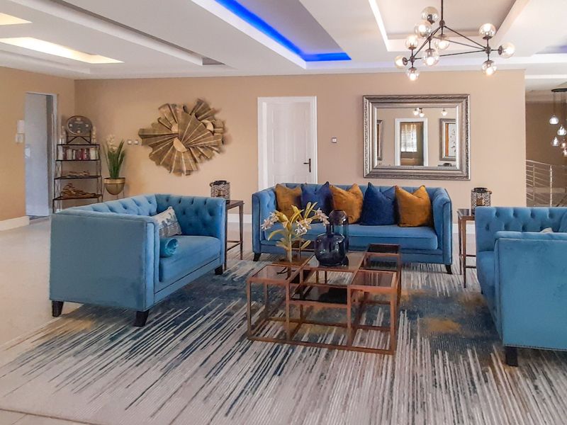 Spacious living room featuring a modern recessed ceiling with integrated LED lighting, a contemporary chandelier, and polished tiled flooring.
