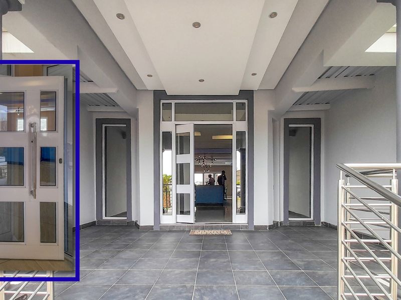 A modern covered entrance porch featuring tiled flooring, recessed ceiling lighting, and a contemporary glass-paneled front door with stainless steel accents.