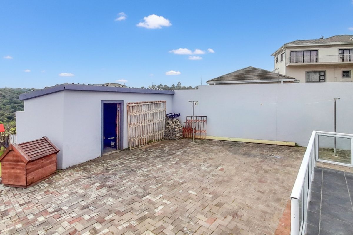 A paved rear courtyard area featuring a boundary wall, glass balustrade, and a small outbuilding, offering potential for outdoor entertainment space.