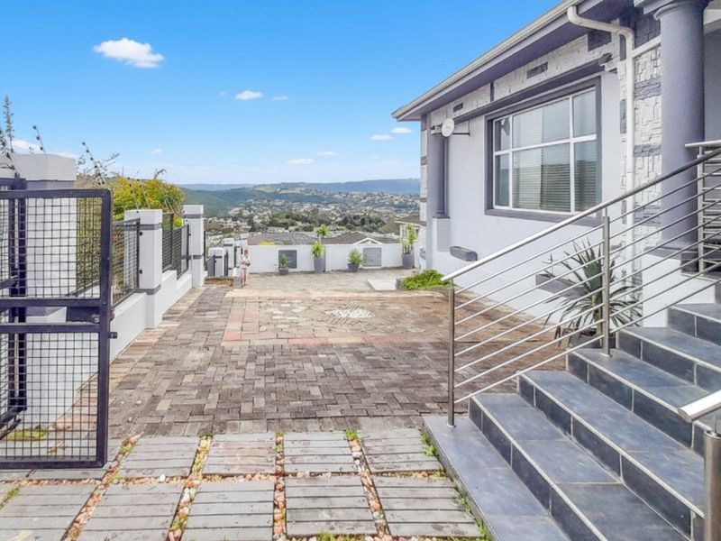 Front entrance area featuring a paved driveway, tiled staircase with stainless steel balustrades, and stone-clad exterior walls with scenic valley views.