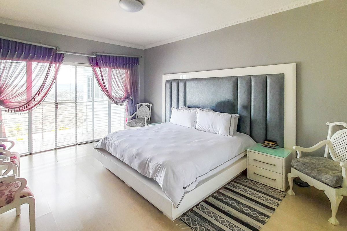 Spacious bedroom featuring a large built-in headboard, crown molding, and sliding glass doors providing access to an outdoor area.