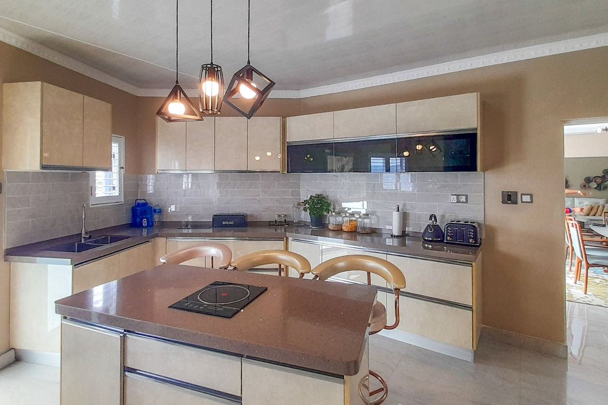 Modern kitchen featuring sleek cabinetry, stone countertops, a central island with an induction cooktop, and a stylish subway tile backsplash.