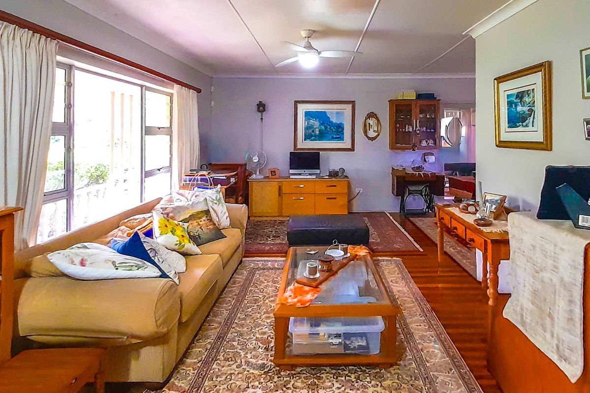 A spacious living room featuring hardwood flooring, a ceiling fan, and large sliding glass doors that provide ample natural light.