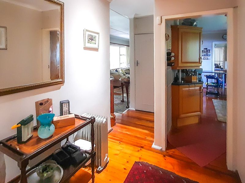 A central hallway featuring polished timber flooring, providing access to the kitchen and living areas of the home.