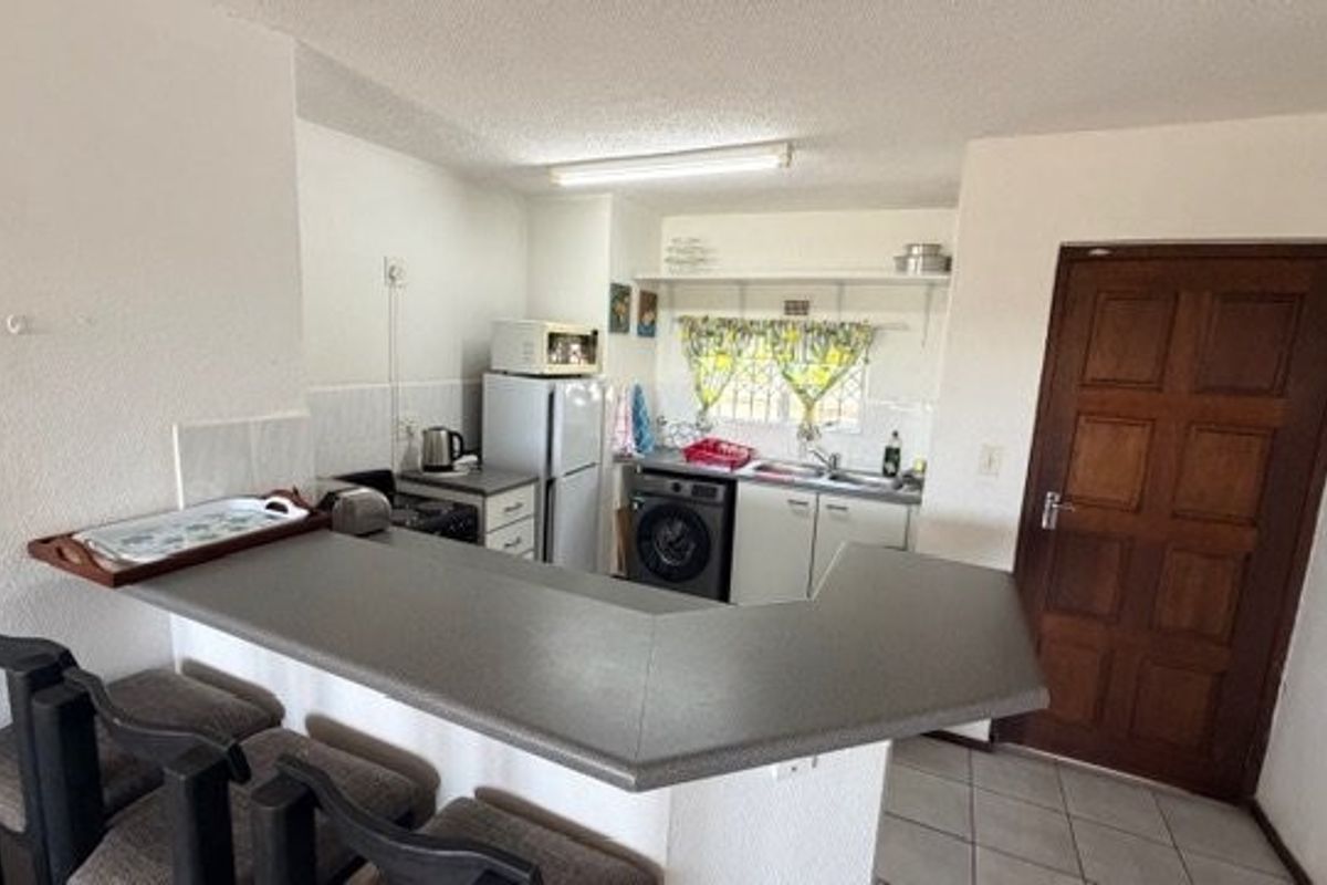 Functional kitchen featuring a breakfast bar, built-in cabinetry, and tiled flooring, offering a practical layout for daily meal preparation.