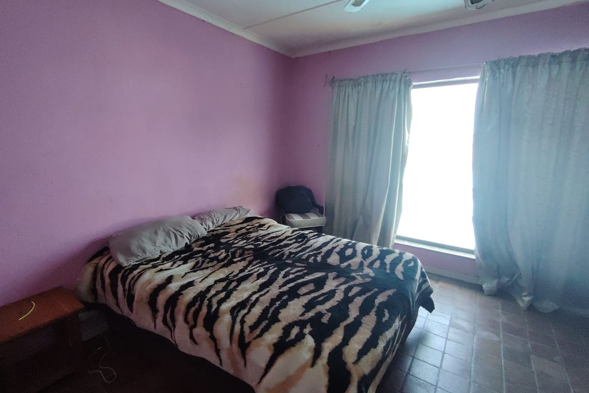 A bedroom featuring tiled flooring and a ceiling fan, currently requiring cosmetic updates to the wall finishes.