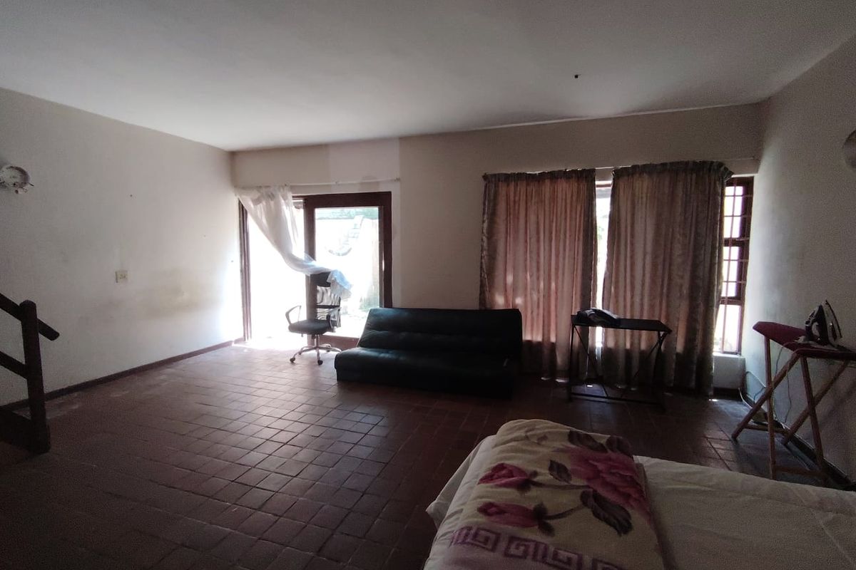 Spacious living area featuring terracotta tile flooring, large windows, and direct access to an outdoor space via a sliding glass door.
