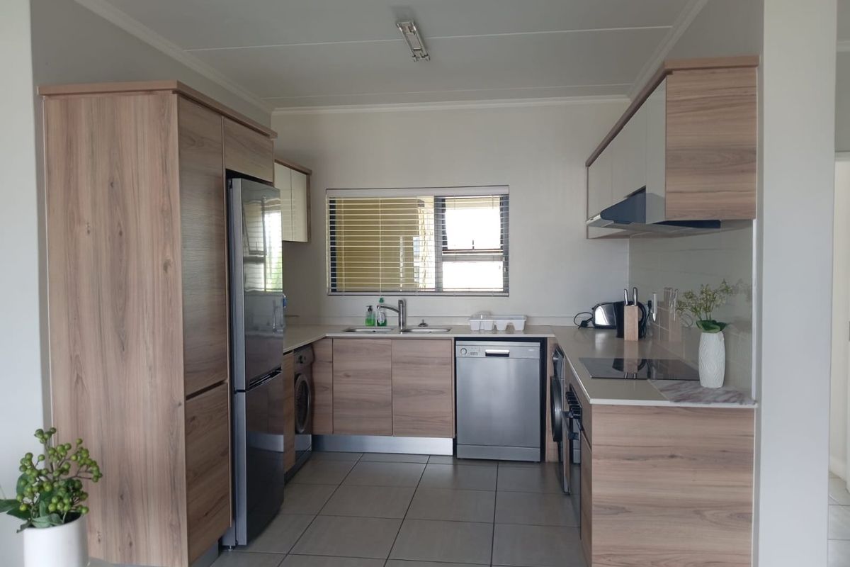 Modern kitchen featuring wood-look cabinetry, stone-effect countertops, integrated appliances, and tiled flooring, offering a clean and functional workspace.