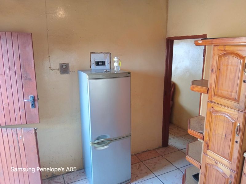 A functional kitchen area featuring tiled flooring and an exposed electrical distribution board, requiring cosmetic updates to improve the overall finish.