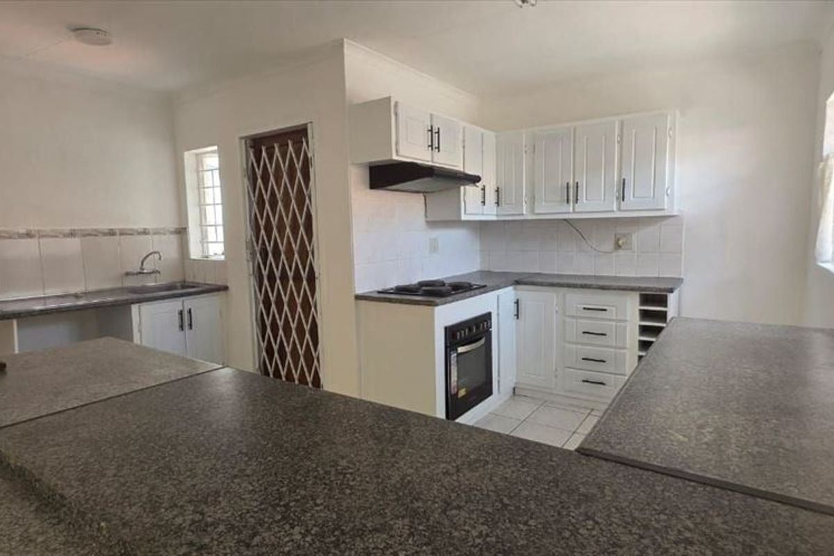 A functional kitchen featuring built-in cabinetry, laminate countertops, a built-in oven with hob, and a double sink, offering a clean and practical workspace.