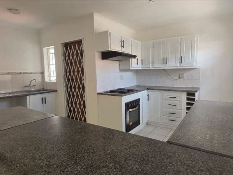 A functional kitchen featuring built-in cabinetry, laminate countertops, a built-in oven with hob, and a double sink, offering a clean and practical workspace.