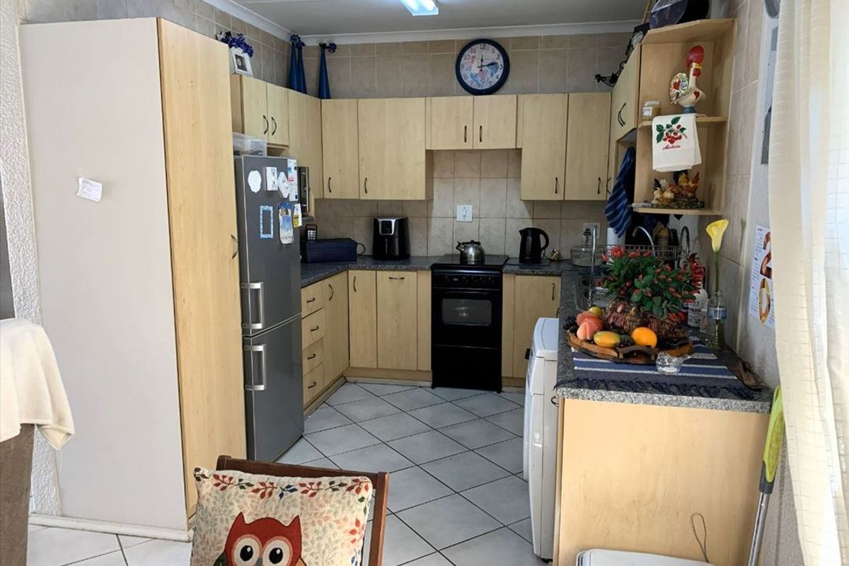 A functional kitchen featuring light wood-tone cabinetry, tiled backsplash, and tiled flooring, providing a practical layout for daily meal preparation.