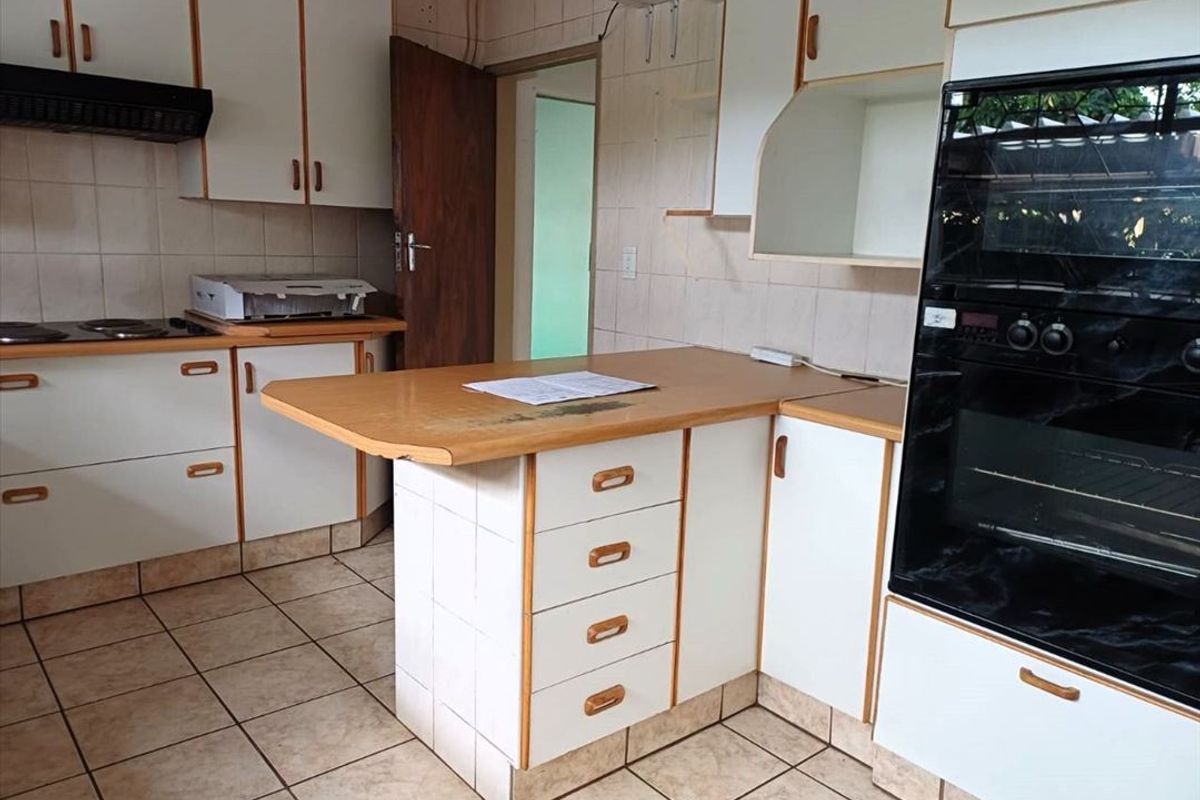 A functional kitchen featuring tiled flooring, built-in cabinetry, an integrated oven, and a central breakfast bar area with a tiled base.