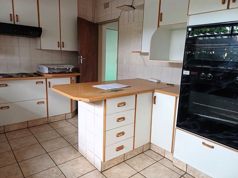 A functional kitchen featuring tiled flooring, built-in cabinetry, an integrated oven, and a central breakfast bar area with a tiled base.