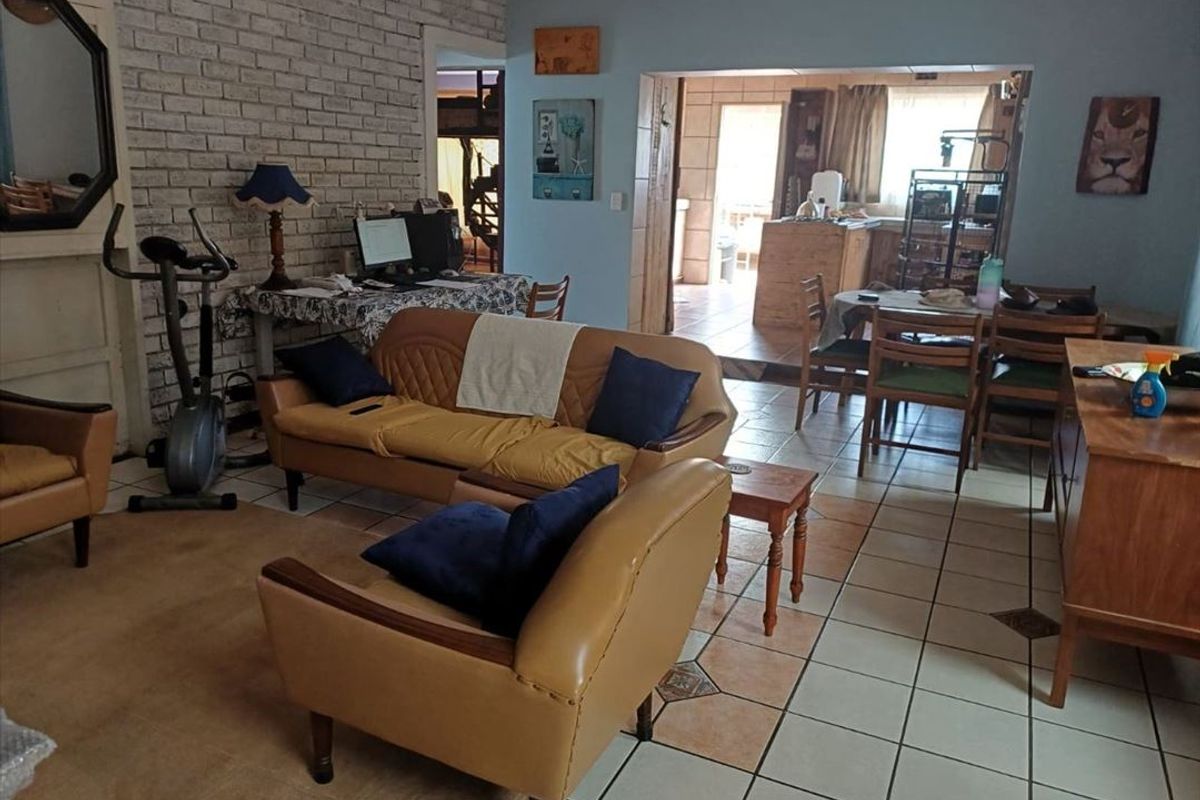 Open plan living and dining area featuring exposed brick wall detailing and ceramic floor tiles, connecting to the kitchen space.