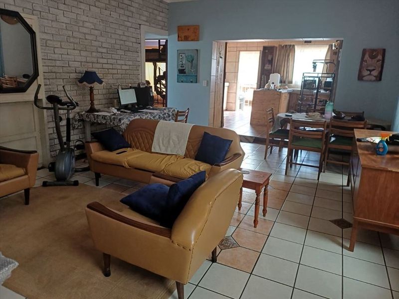 Open plan living and dining area featuring exposed brick wall detailing and ceramic floor tiles, connecting to the kitchen space.