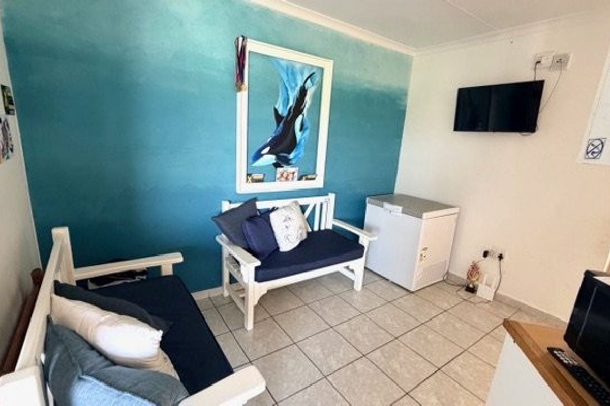 A compact living area featuring tiled flooring and a painted feature wall, providing a functional space for relaxation.