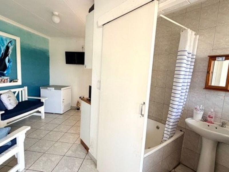 Open plan living area featuring tiled flooring and an integrated bathroom with a pedestal basin and bathtub.
