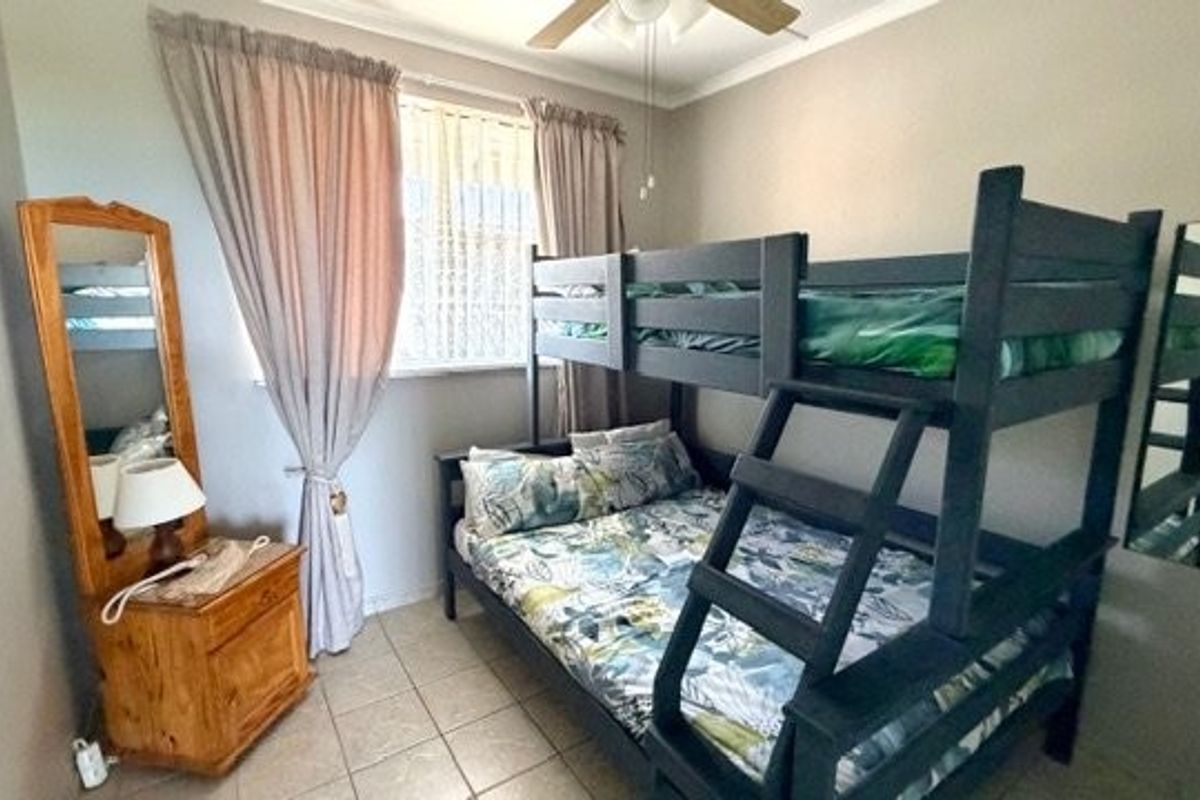 A functional bedroom featuring tiled flooring, a ceiling fan, and a window with curtain treatments.