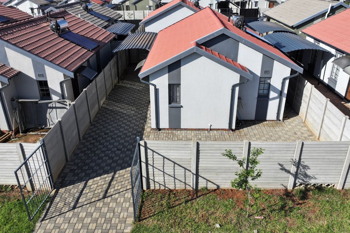 Aerial view of a residential property featuring a tiled roof, paved driveway, and secure precast concrete boundary walls in a suburban estate setting.