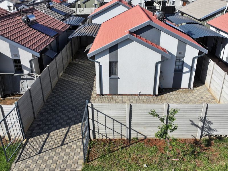 Aerial view of a residential property featuring a tiled roof, paved driveway, and secure precast concrete boundary walls in a suburban estate setting.