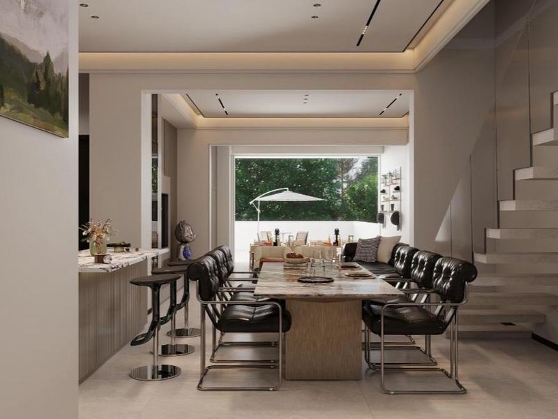 Modern open-plan living and dining area featuring a striking floating staircase, stone kitchen island, and seamless transition to an outdoor patio space.