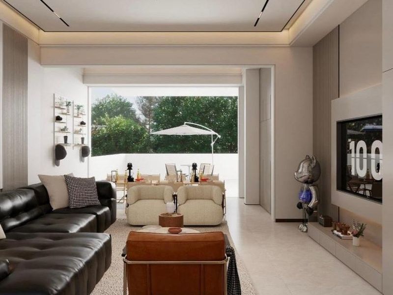 Modern open-plan living area featuring sleek built-in media cabinetry, recessed ceiling lighting, and seamless transition to an outdoor patio space.