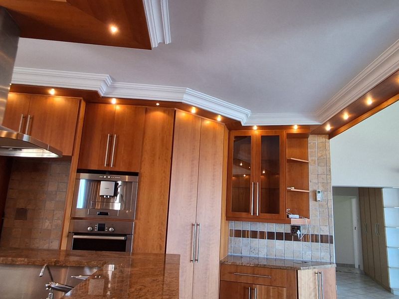 A well-appointed kitchen featuring warm wooden cabinetry, granite countertops, integrated stainless steel appliances, and elegant crown molding with recessed lighting.