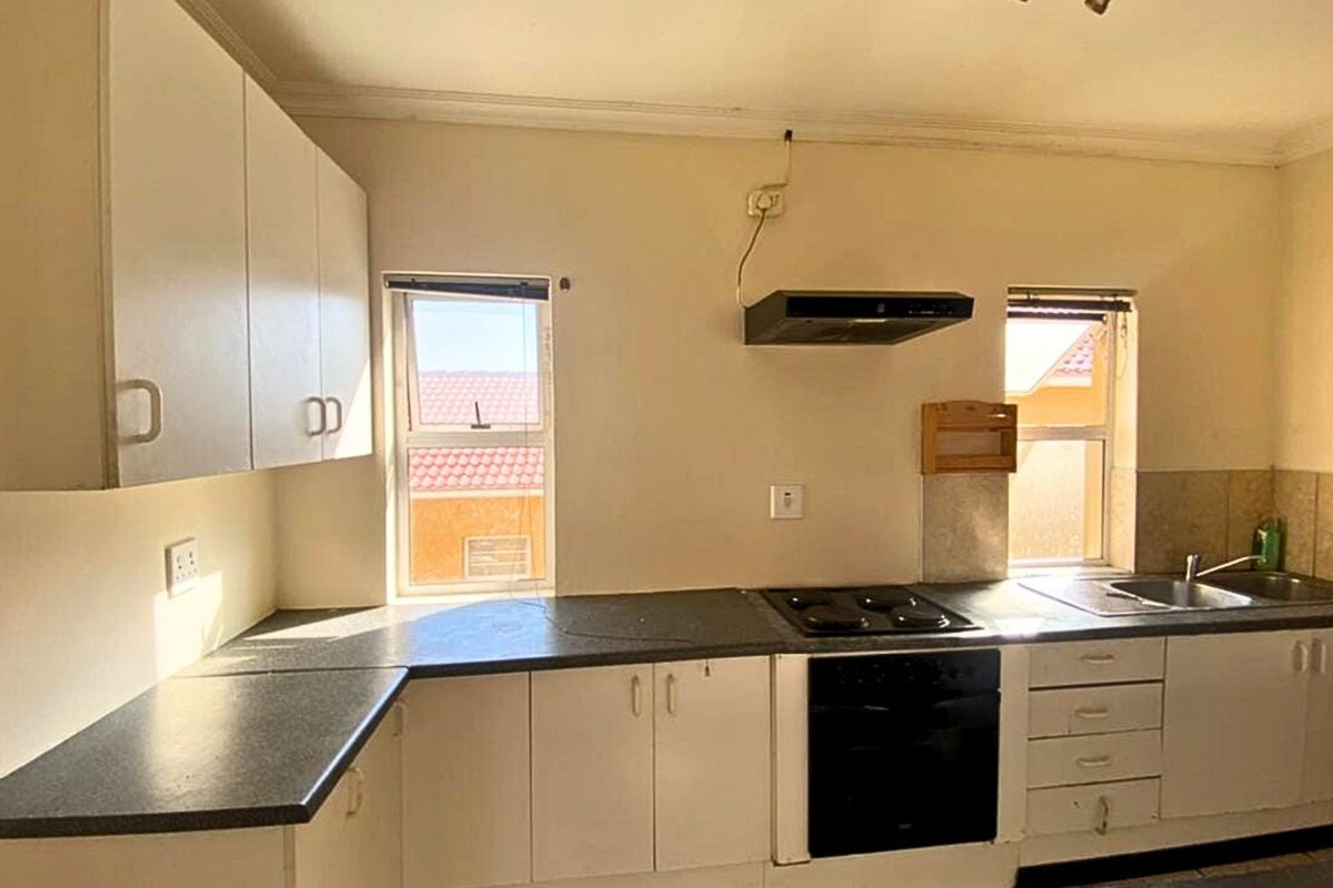 A functional kitchen featuring built-in cabinetry, laminate countertops, a built-in oven with hob, and a stainless steel double sink.