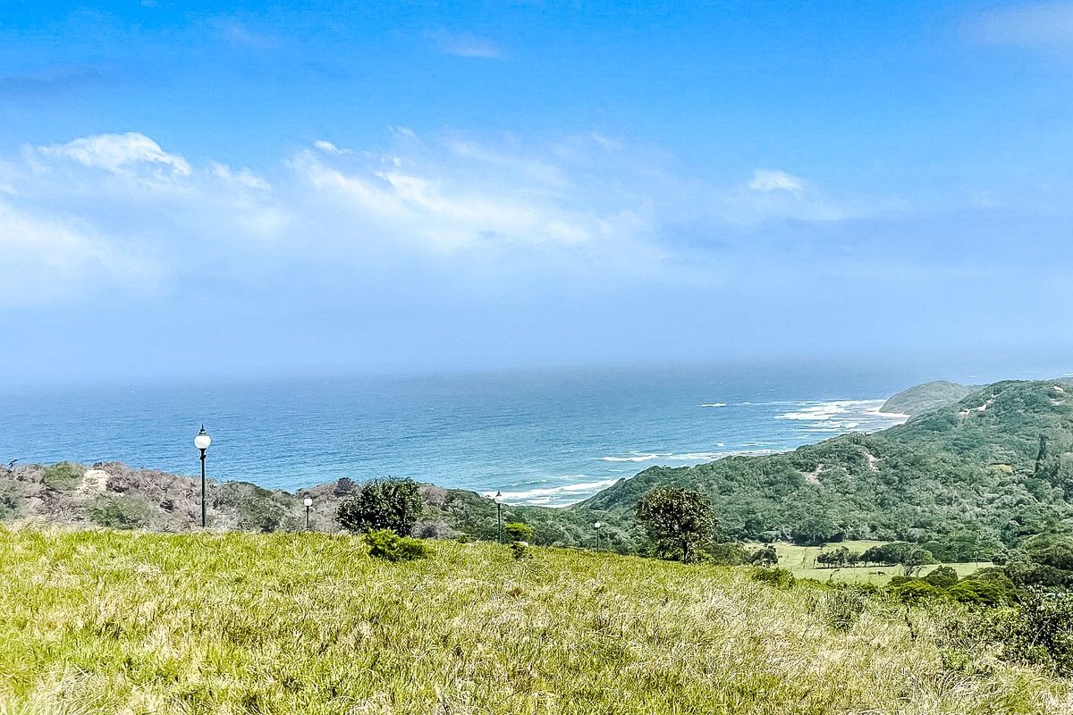 A scenic elevated view overlooking the coastline, featuring rolling green hills and ocean vistas from the vacant residential land.