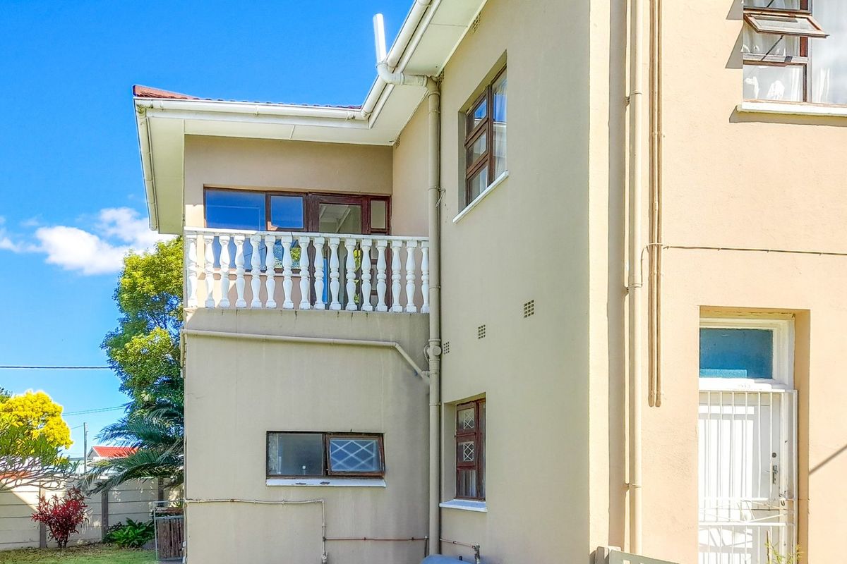 Rear elevation of the property featuring a balcony with a balustrade, security gates, and exterior wall finishes.