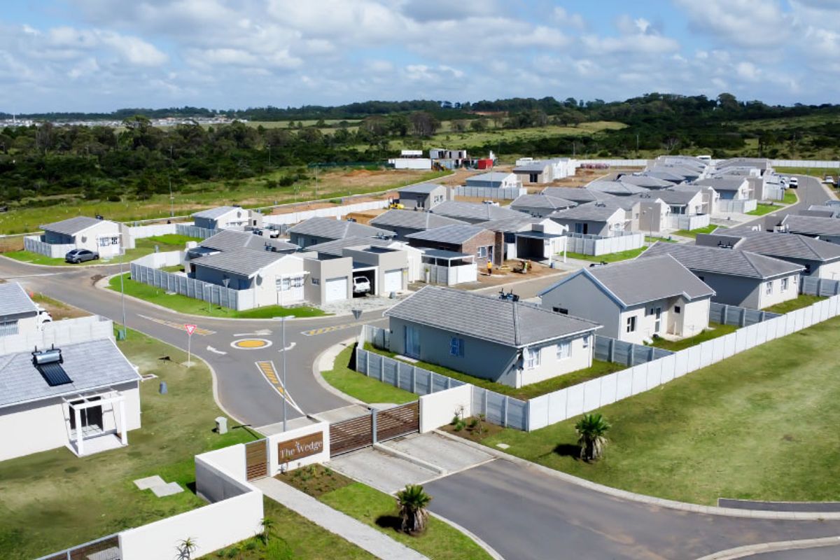 Aerial view of The Wedge residential estate, showcasing multiple detached homes, paved internal roads, and secure perimeter fencing in a suburban setting.