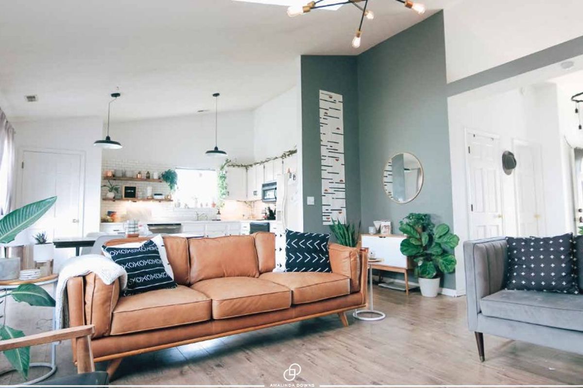Spacious open-plan living area featuring vaulted ceilings, modern lighting, and a seamless flow into the kitchen with built-in cabinetry and shelving.