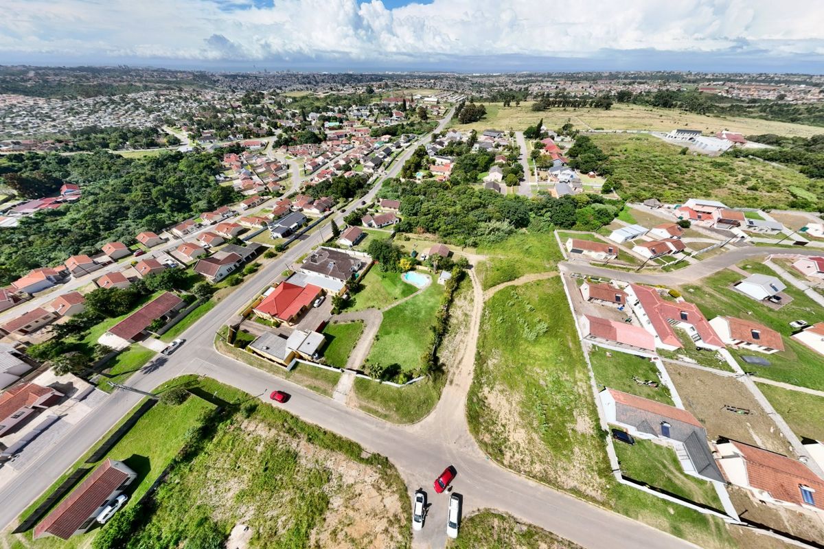 An aerial view of a residential neighborhood showing established housing, road infrastructure, and surrounding vacant land parcels.