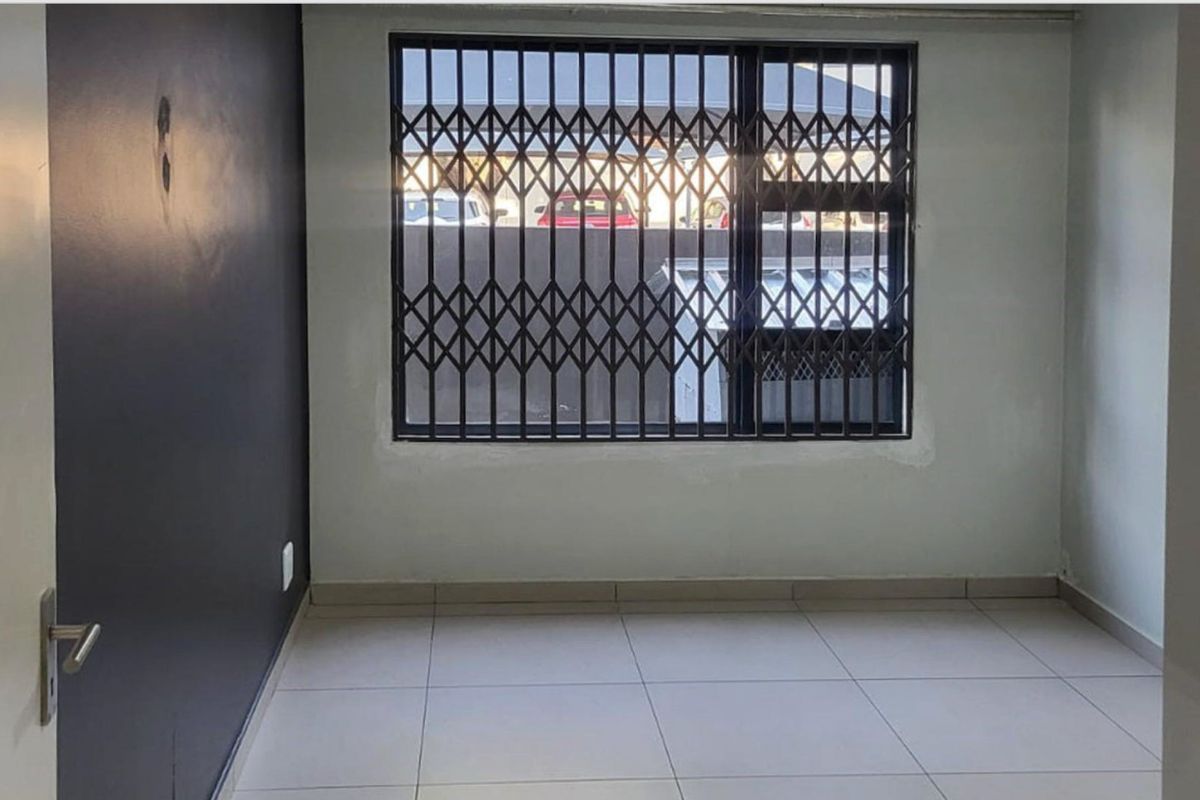 An empty bedroom featuring tiled flooring and a security gate on the window, requiring minor cosmetic repairs to the walls and paintwork.