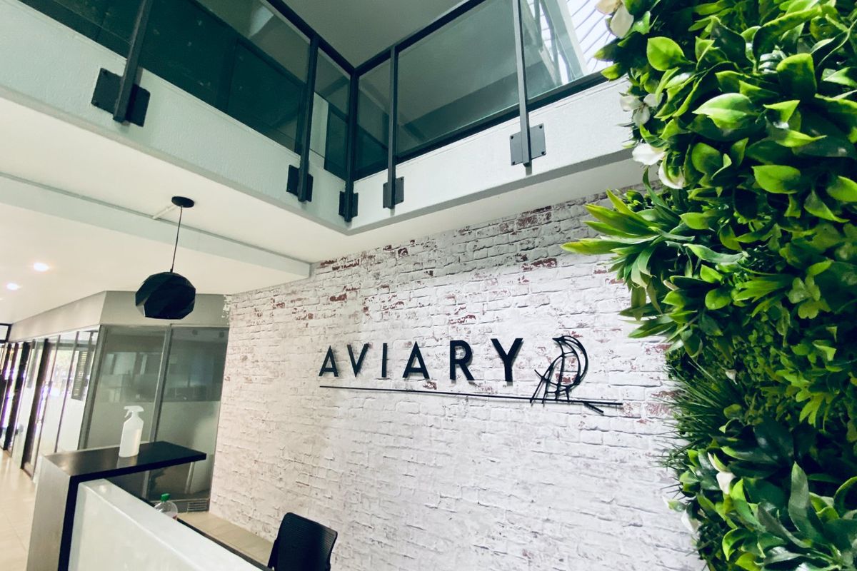 Modern commercial entry foyer featuring a reception desk, exposed brick feature wall, and a mezzanine level with glass balustrades.