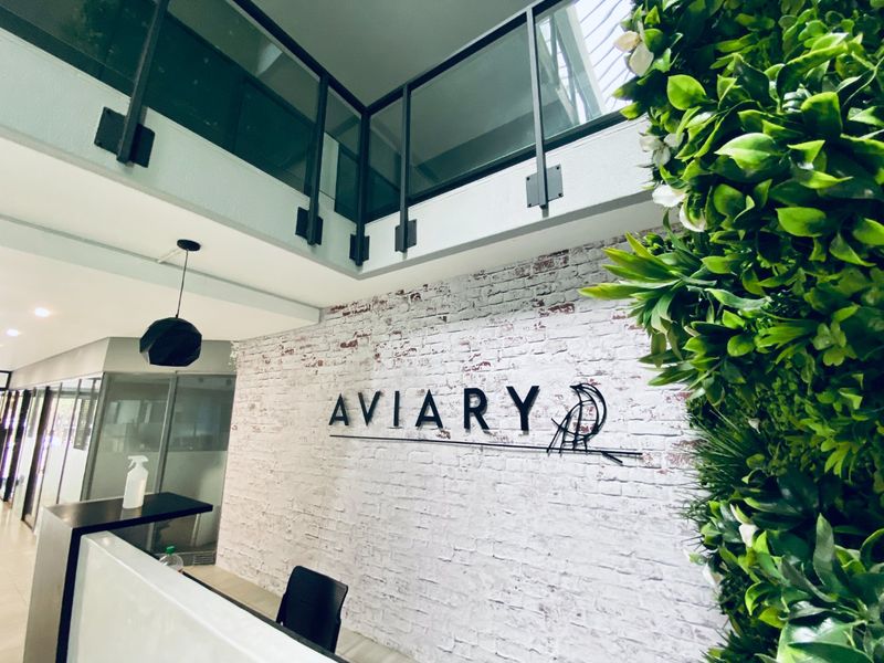 Modern commercial entry foyer featuring a reception desk, exposed brick feature wall, and a mezzanine level with glass balustrades.