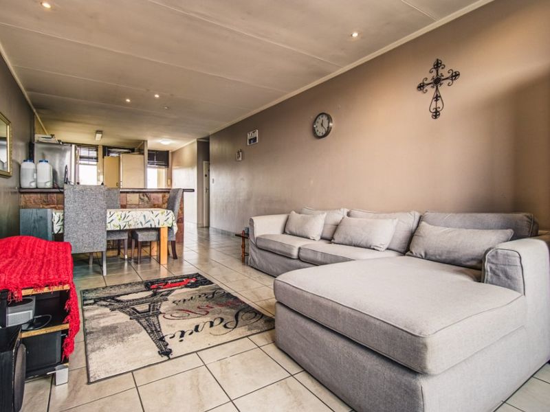 Open-plan living and dining area featuring tiled flooring, recessed lighting, and a breakfast bar connecting to the kitchen space.