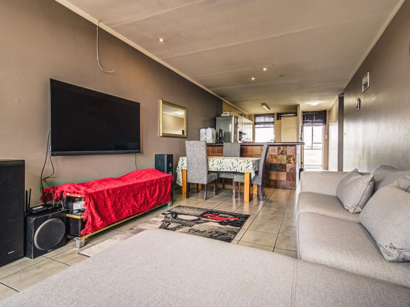 Open-plan living and dining area featuring tiled flooring, recessed lighting, and a stone-clad breakfast counter connecting to the kitchen space.