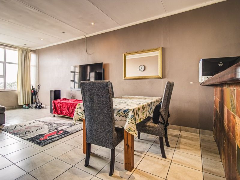 Open-plan living and dining area featuring tiled flooring, recessed lighting, and a breakfast bar with a tiled finish.