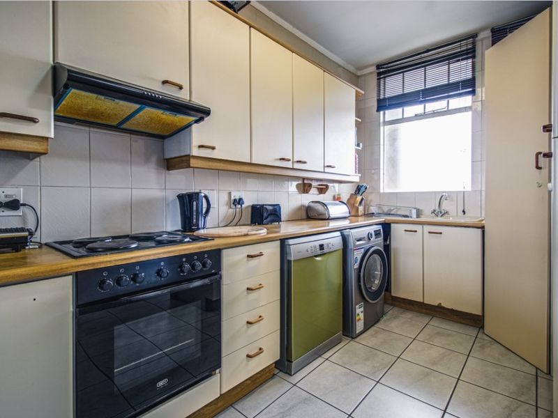 A functional kitchen featuring built-in cabinetry, laminate countertops, a built-in oven with hob, and integrated space for laundry appliances.