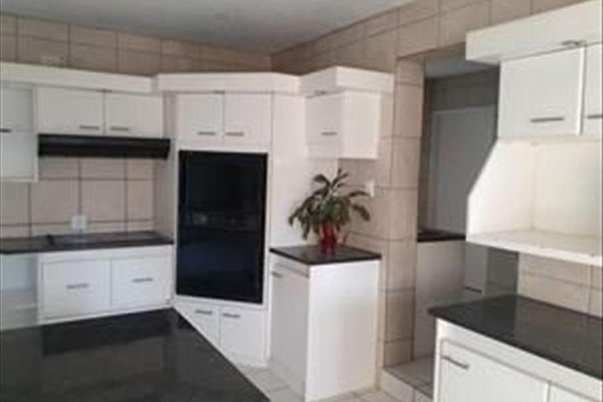 A functional kitchen featuring white built-in cabinetry, dark granite countertops, and tiled finishes, offering a clean canvas for potential modern updates.