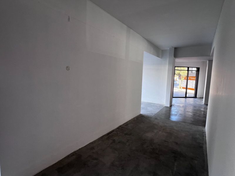 A bright, open-plan commercial space featuring polished concrete floors and large glass storefront windows, ideal for retail or office use.
