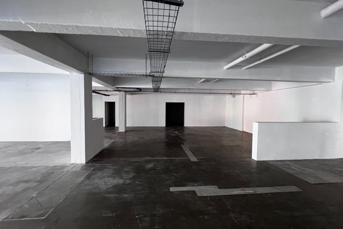 An expansive, open-plan commercial utility or storage space featuring exposed industrial ceiling infrastructure, concrete flooring, and structural columns.