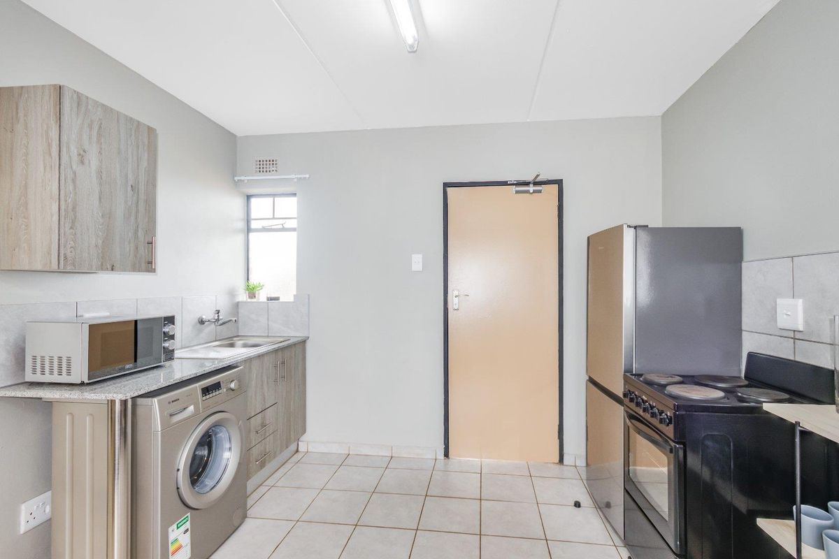 Functional kitchen featuring tiled flooring, built-in cabinetry, stainless steel sink, and space for major appliances.