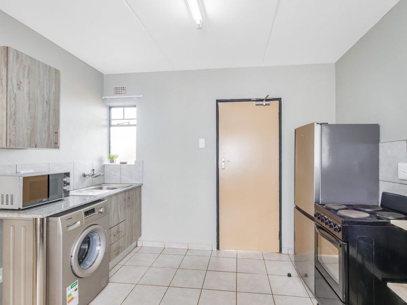 Functional kitchen featuring tiled flooring, built-in cabinetry, stainless steel sink, and space for major appliances.