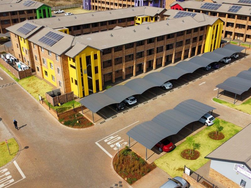 Aerial view of a multi-story residential complex featuring brick architecture, solar panels, and dedicated covered carport parking bays.
