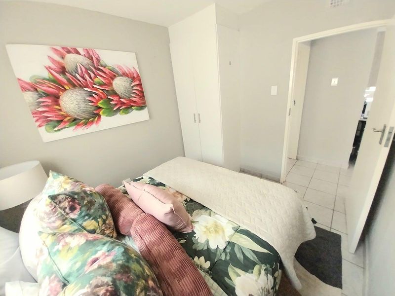 A well-maintained bedroom featuring neutral wall tones, tiled flooring, and a functional built-in wardrobe.
