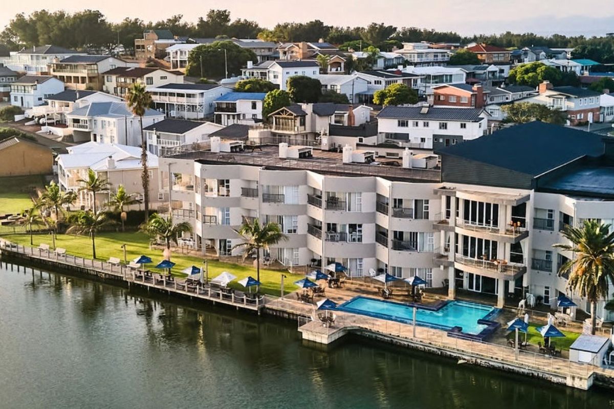 Aerial view of a multi-story commercial waterfront property featuring a swimming pool, landscaped lawn, and direct access to the water.